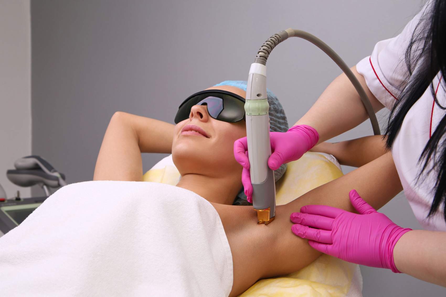 Blonde woman having underarm Laser hair removal epilation. Laser treatment in cosmetic salon.