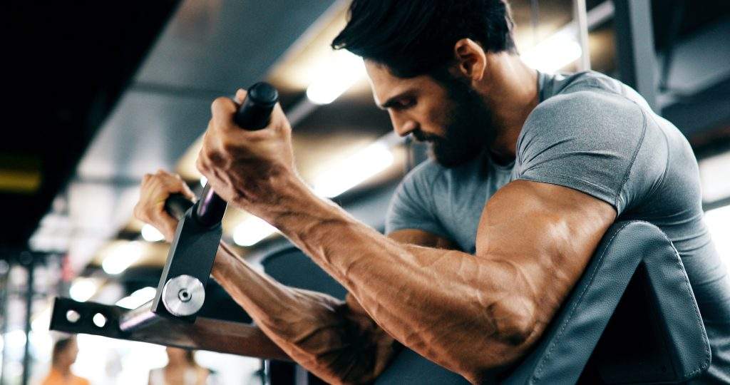 Young handsome strong man doing exercises in gym