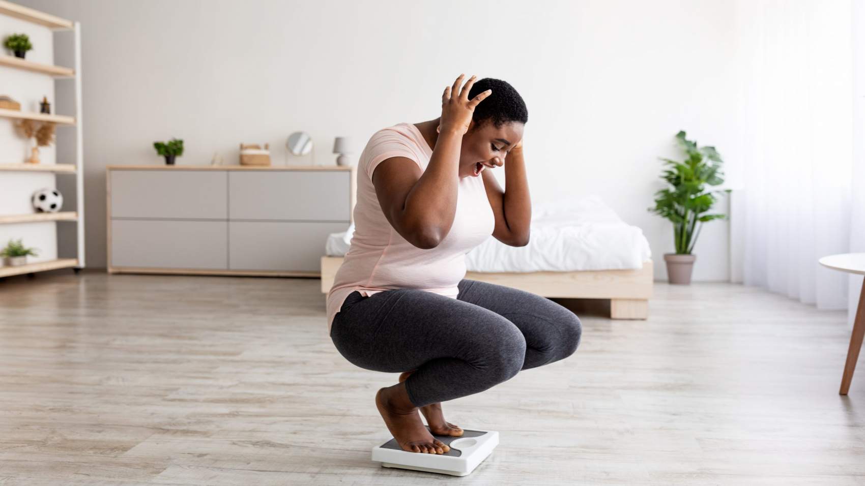 Plus size black woman cannot believe her weight loss result, shouting OMG, sitting on scales at home, feeling excited about slimming success, celebrating achievement, copy space. Panorama